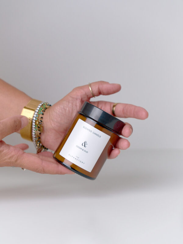 Candela Cedar & Oud 135 g in vetro ambrato dettaglio con mani