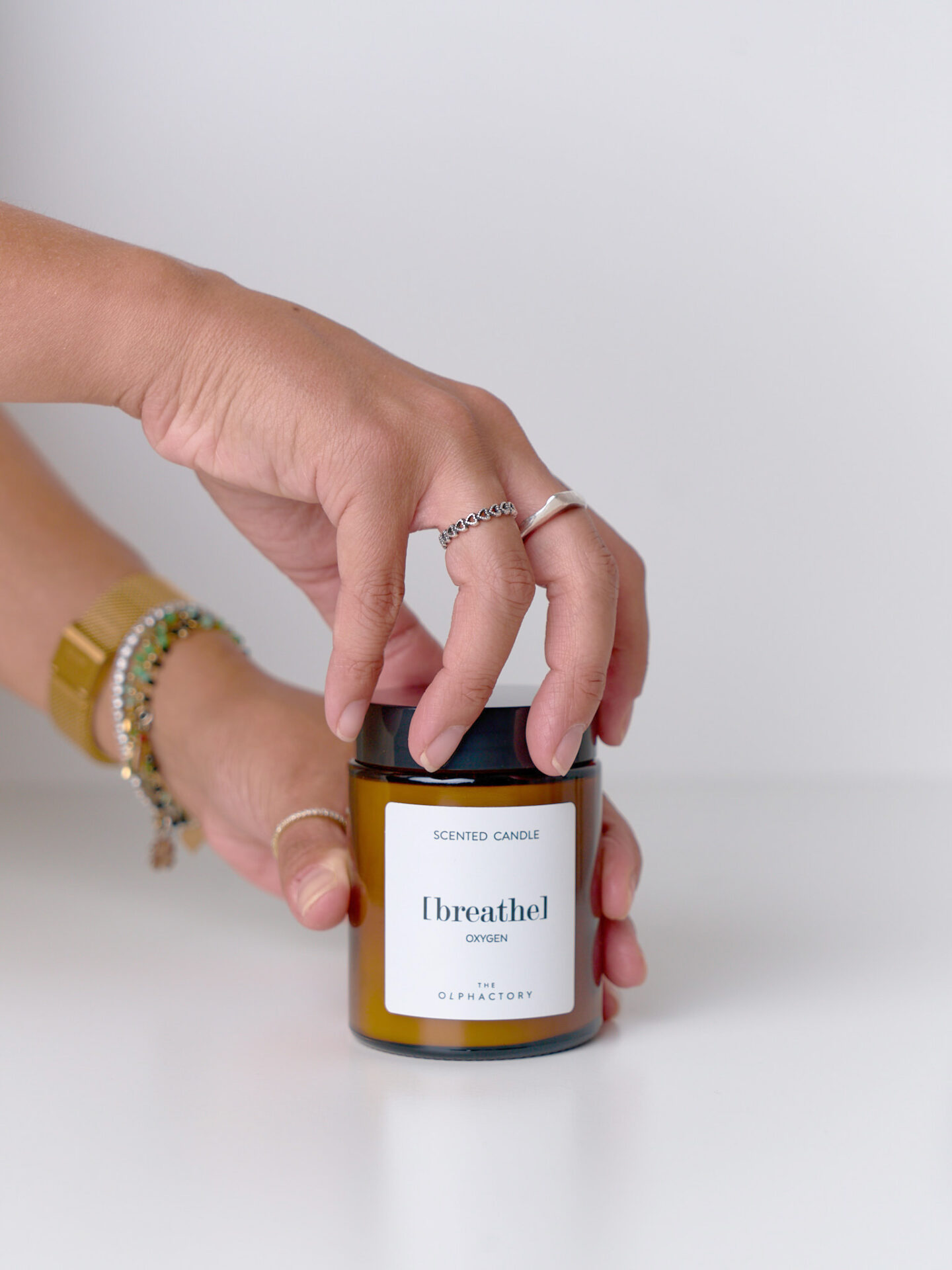 Candela Oxygen 135 g in vetro ambrato, mani che aprono il tappo