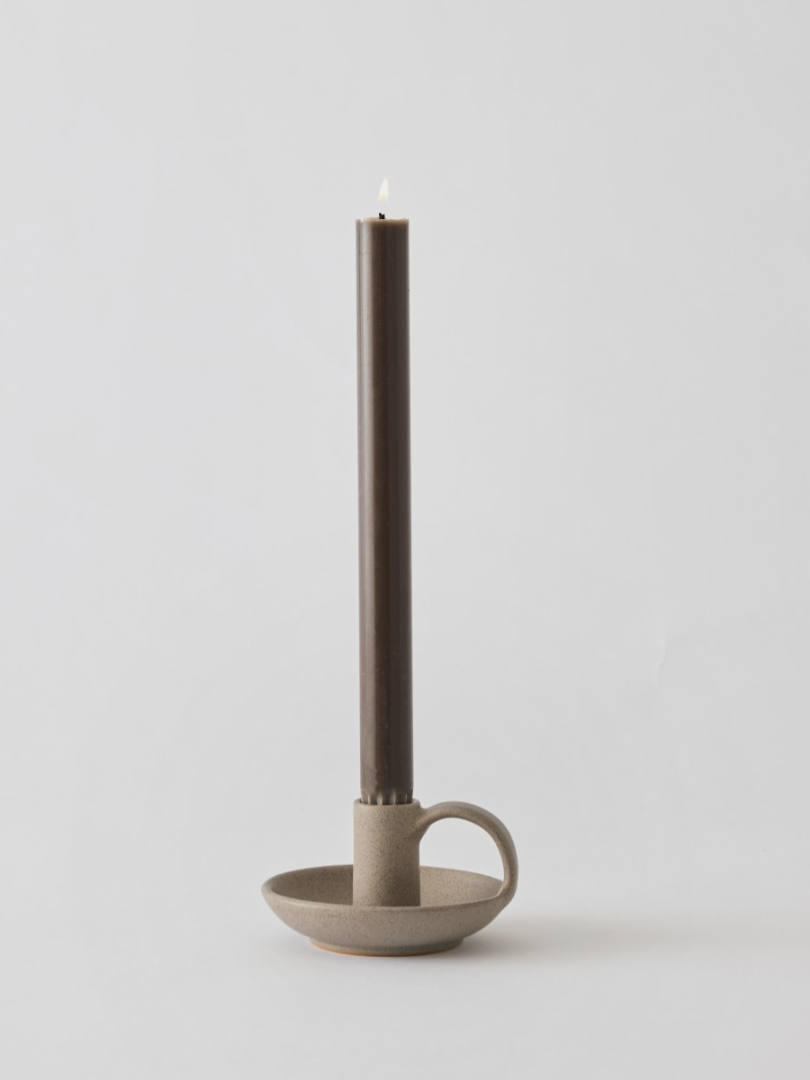 Porta candela in ceramica con candela, luce calda e atmosfera rilassante.