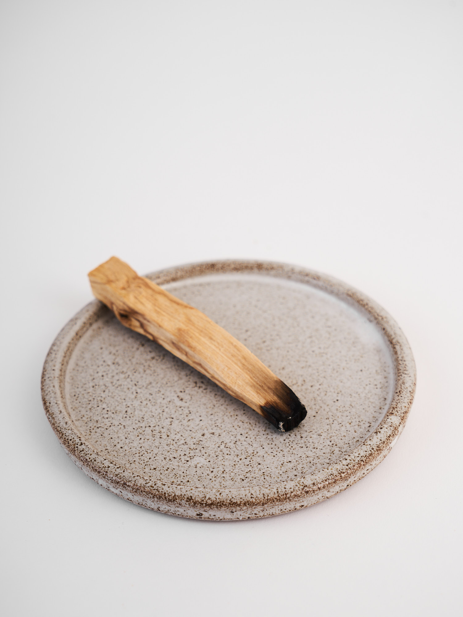 Piattino in gres puntinato con un bastoncino di palo santo appoggiato